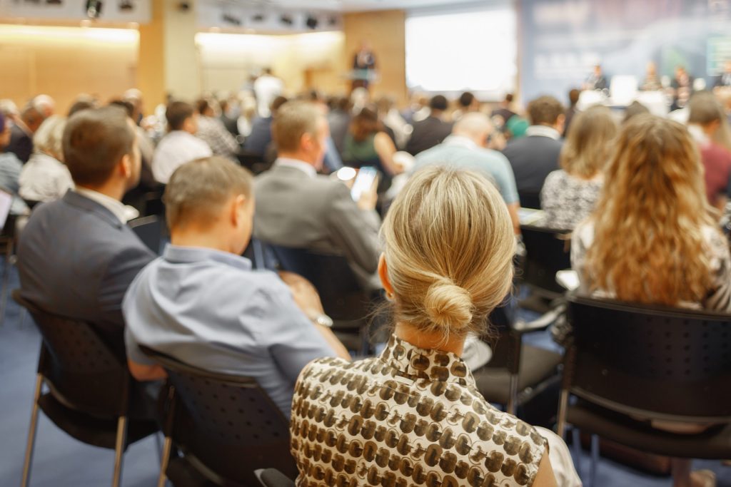 People are seated in an auditorium for a meeting