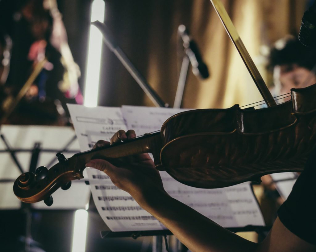 Image of hand holding violin silhouetted against music stand