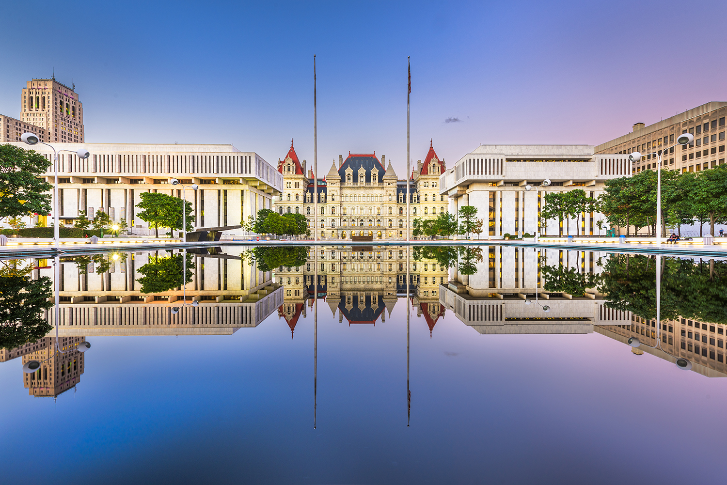 The New York State Legislative buildings are shown reflected in the Reflecting Pool