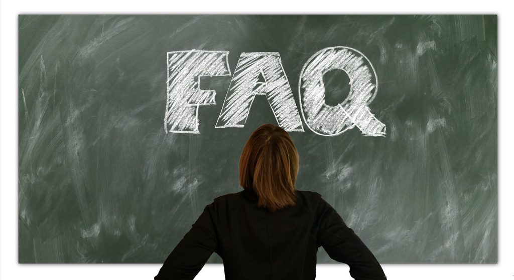 An individual staring at a blackboard that says "FAQ" in white chalk.