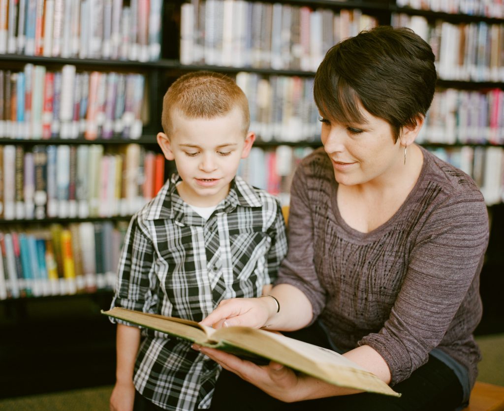 An adult shows a child a book