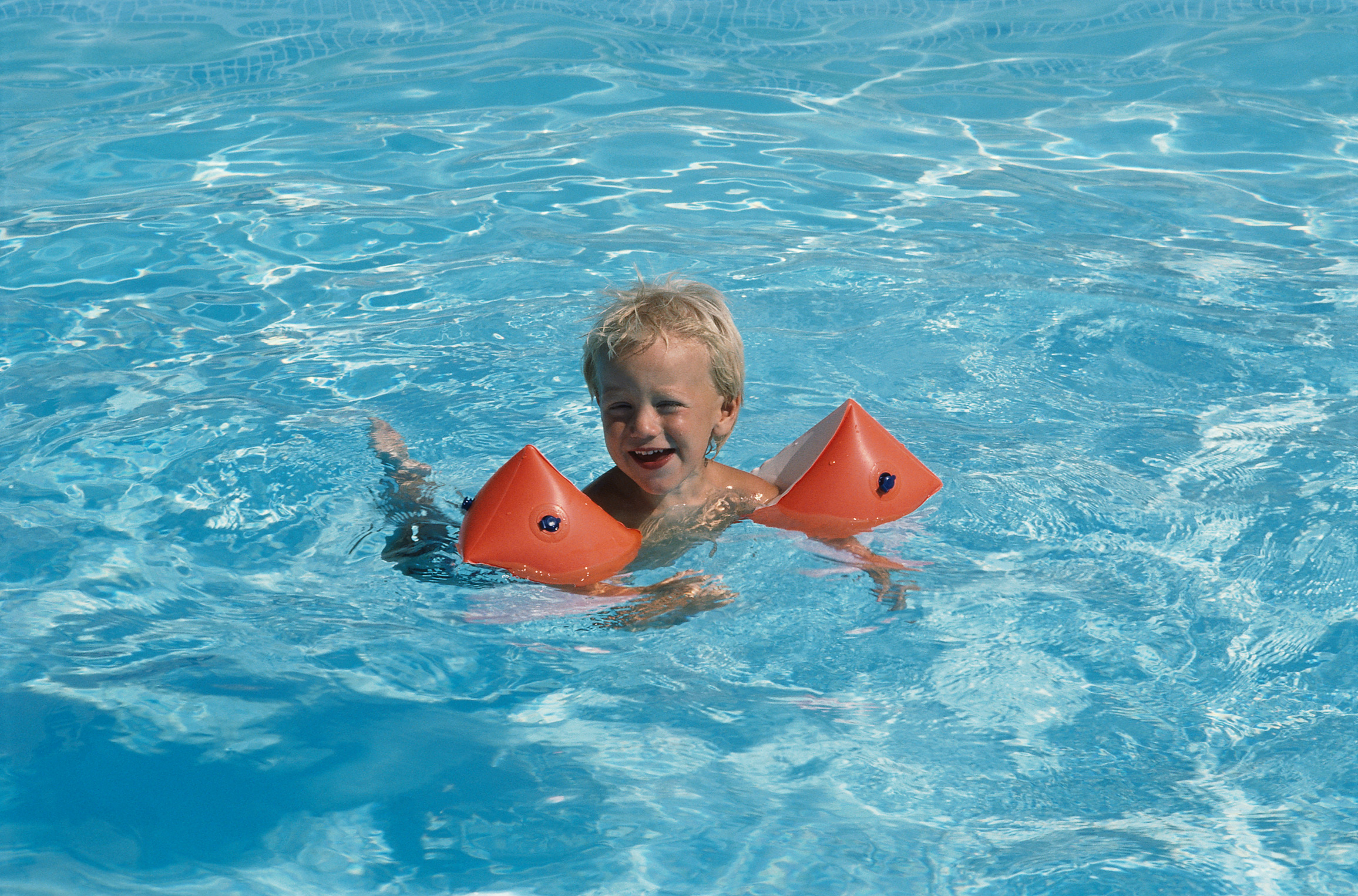child in swim floaties in a pool
